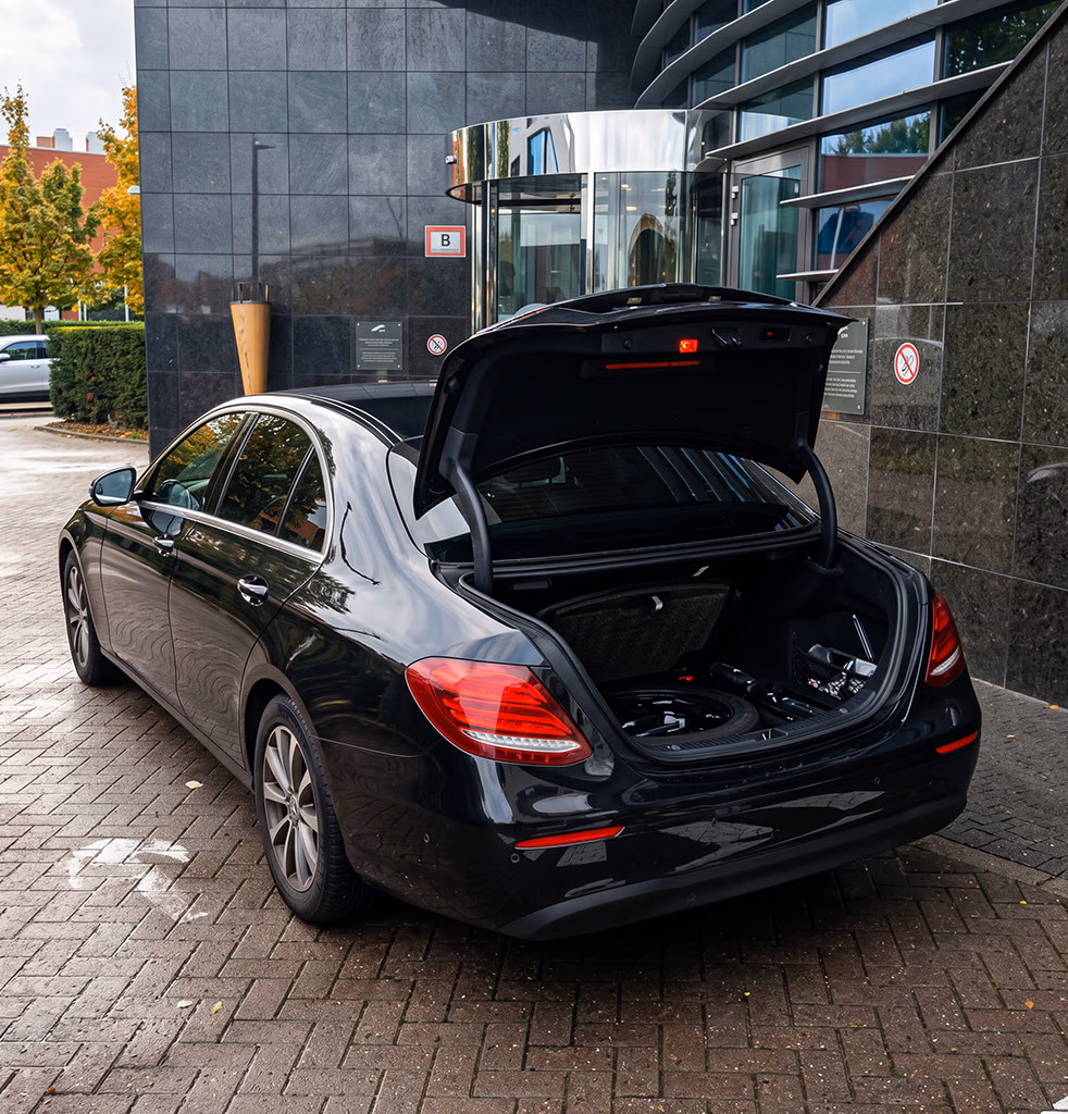 Amsterdam taxi — black Mercedes E-Class with open boot for luggage outside an Amsterdam building