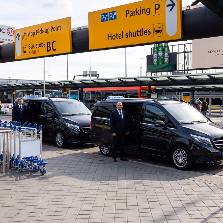 Two Toursnl chauffeurs with black Mercedes vans at the Amsterdam Schiphol pick-up point