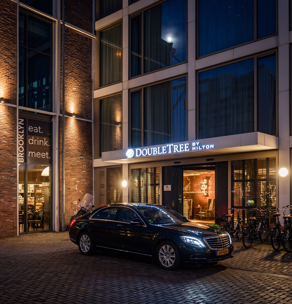 Toursnl VIP Amsterdam taxi, a black Mercedes S-Class, waiting at night outside the DoubleTree by Hilton hotel in central Amsterdam