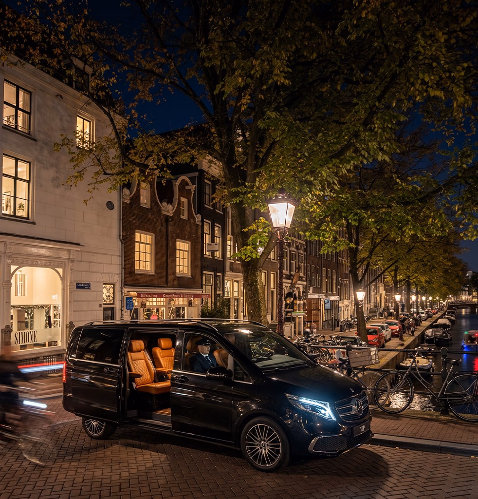 فان مرسيدس V-Class فاخر VIP مع سائق متوقف على ضفة قناة في أمستردام ليلاً